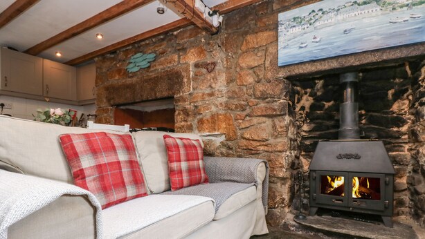 A cozy living room with a stone fireplace, a sofa with plaid cushions, and a painting on the wall.