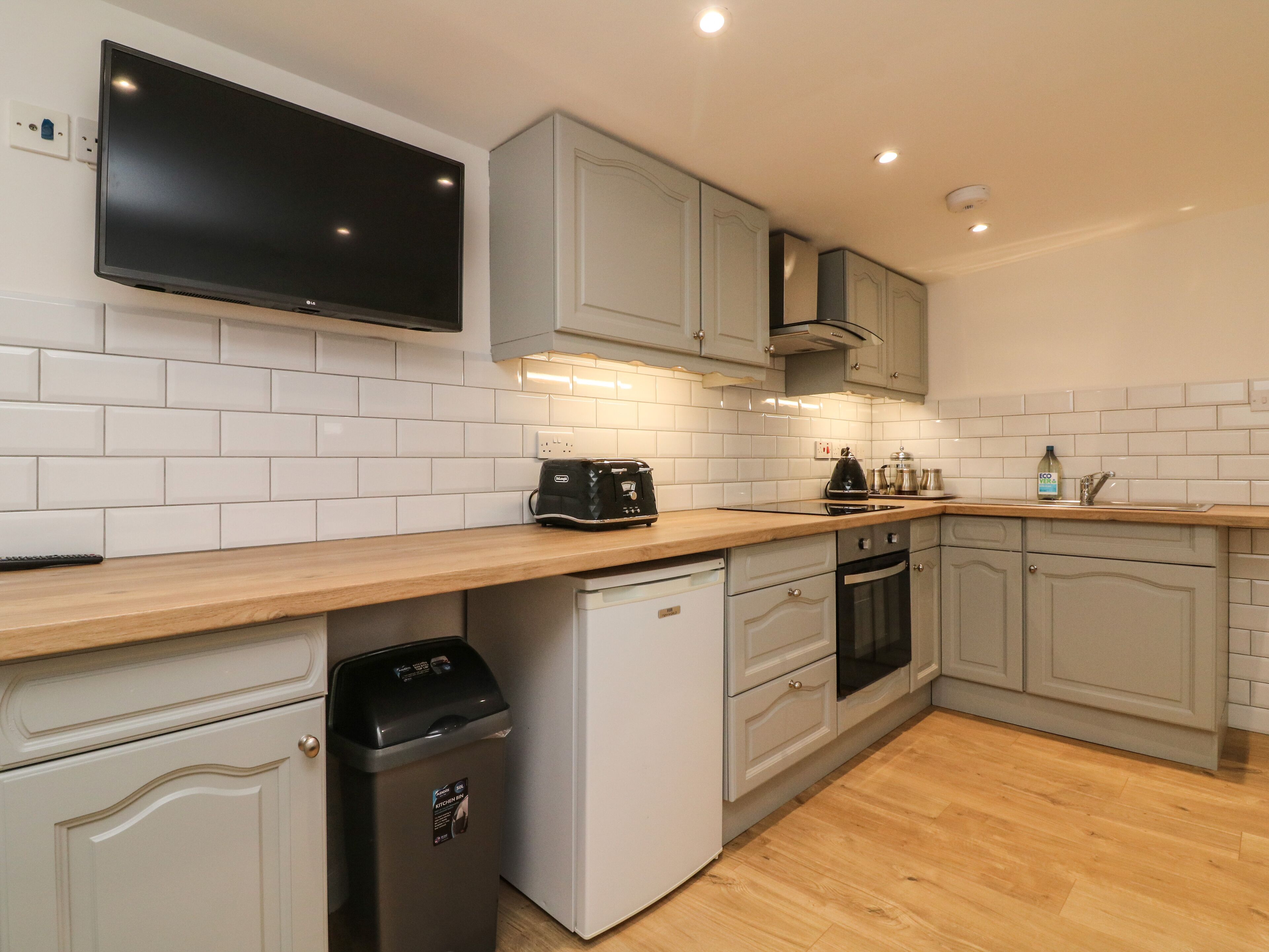 A modern kitchen with white cabinetry, a built-in oven, and a dishwasher.