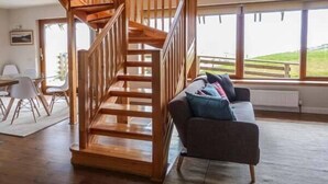 A wooden staircase leading to a loft area with a view of the outdoors.