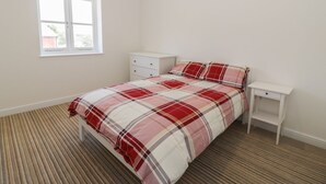 Una camera da letto con un letto, un comodino, una cassettiera e una finestra.