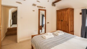 A bedroom with a bed, wooden wardrobe, and a mirror. - Broadwood Barn (Hope Valley)