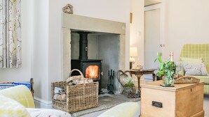 A cozy living room with a fireplace, a wicker basket, a wooden chest, and a green sofa. - St. John's Cottage (Sheffield)