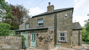 A stone house with a green door, a small window, and a chimney. - St. John's Cottage (Sheffield)