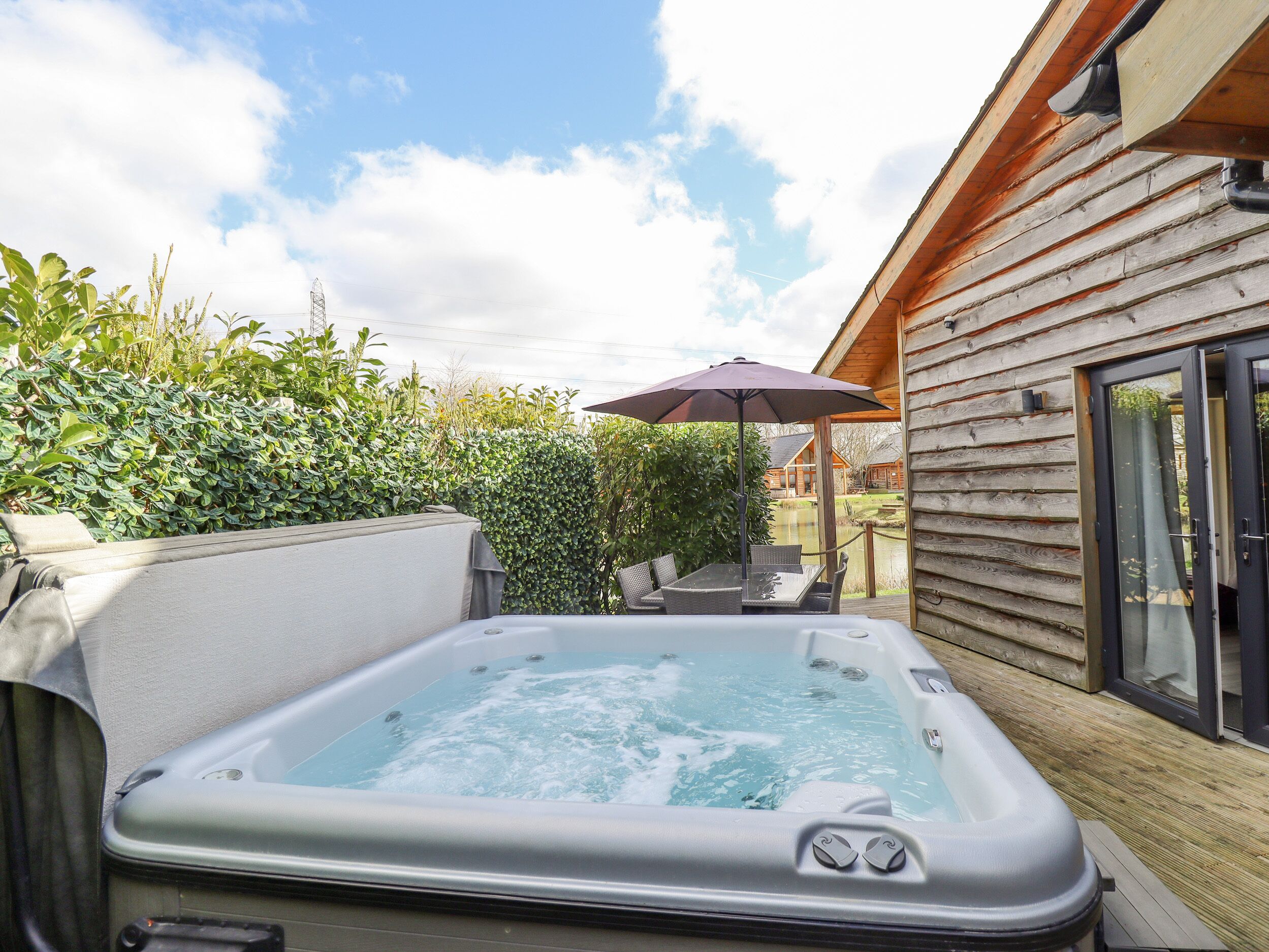 A hot tub in a wooden cabin with a patio area, surrounded by greenery.