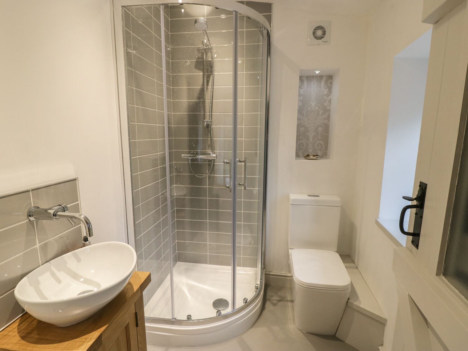 Ein modernes Badezimmer mit einer Glasdusche, einem weißen Waschbecken und einer Toilette.