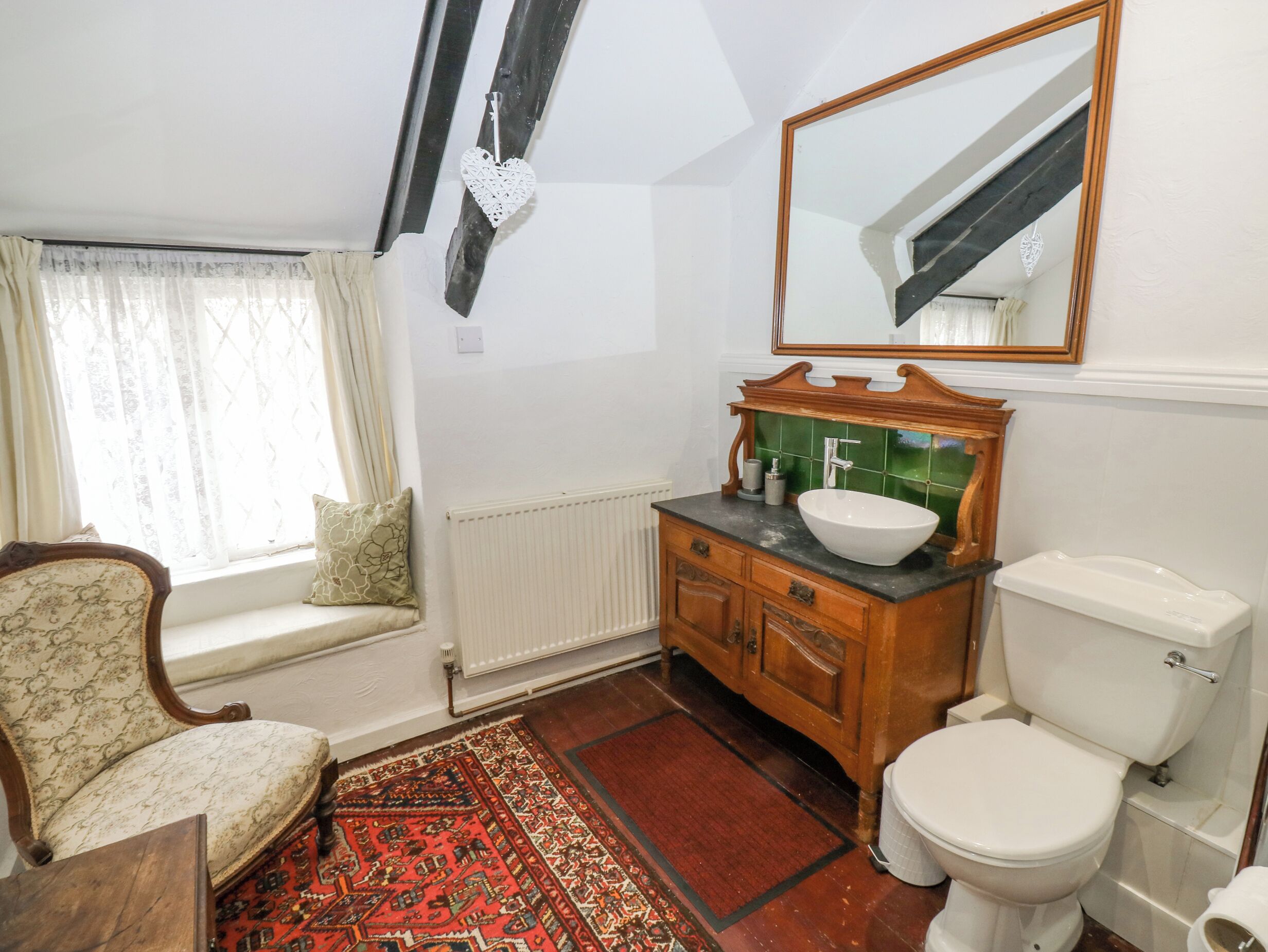 A bathroom with a wooden vanity, white toilet, and a large mirror.