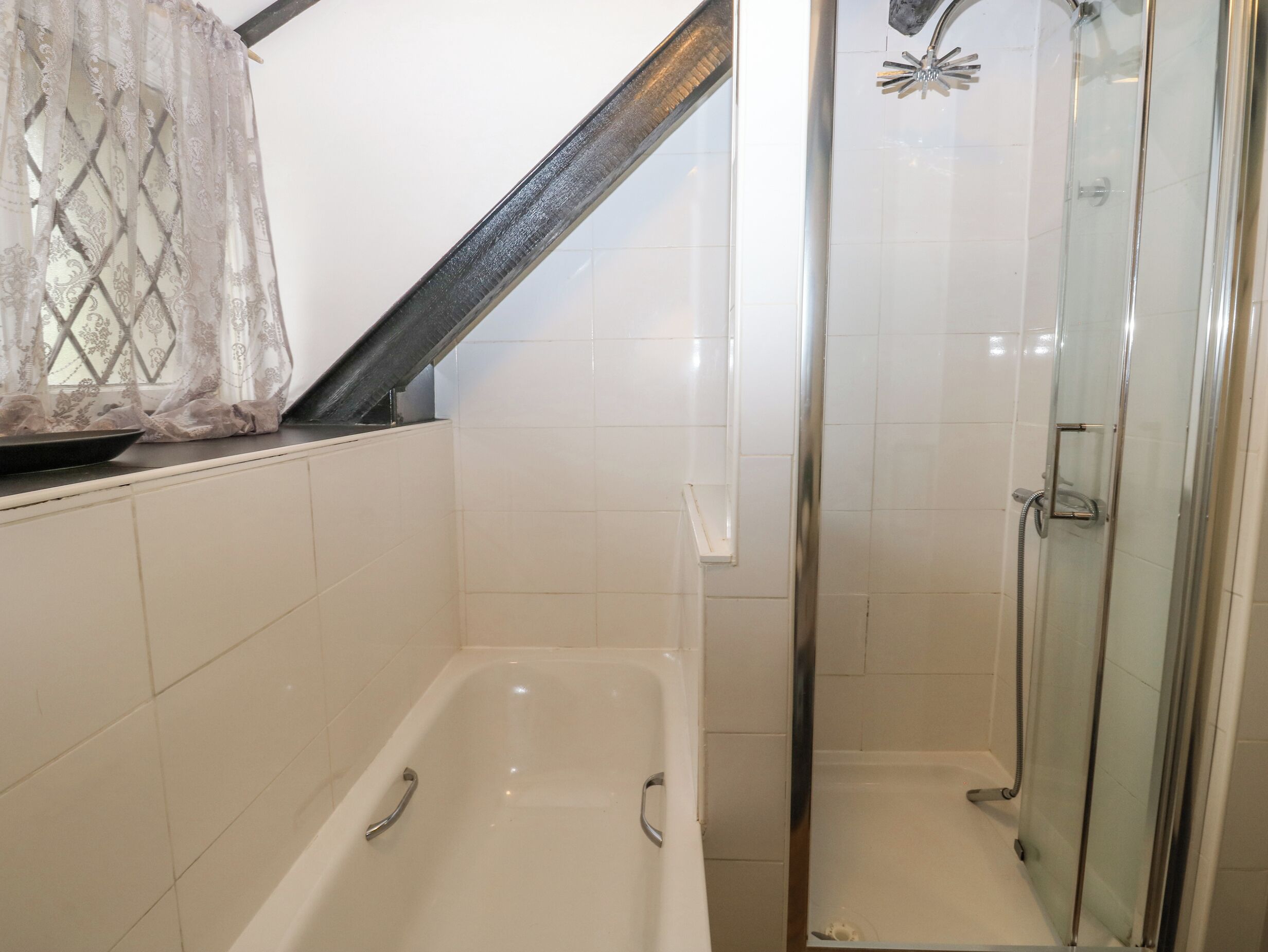 Ein Badezimmer mit einer Badewanne, einer Dusche und einem Glaskabinentrennenden Duschbereich.