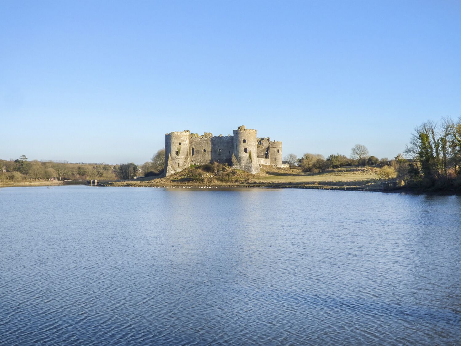 Un château historique, doté d’un fossé et entouré d’un paysage naturel.