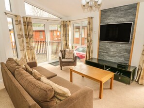 Una sala de estar moderna con un sofá, una mesa de centro y un televisor montado en una pared de piedra.