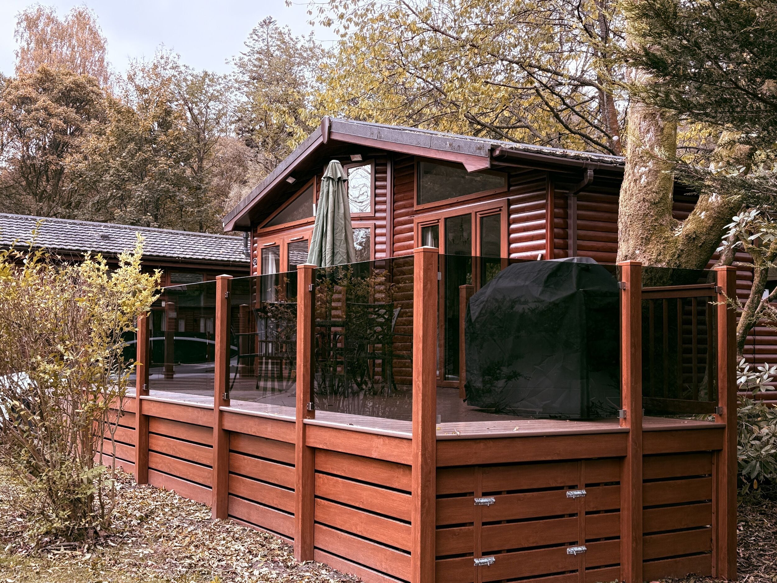 A wooden cabin with a covered deck, surrounded by trees.
