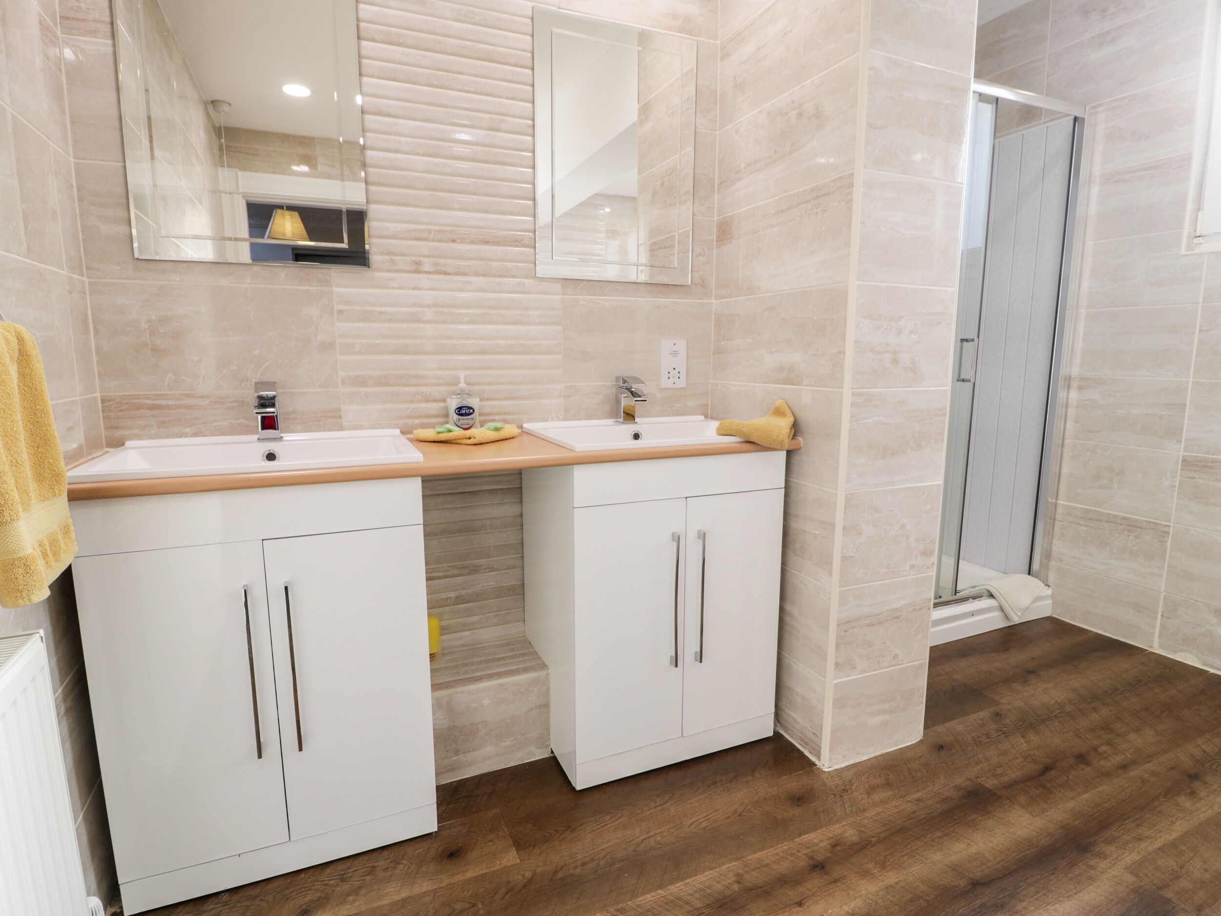 Ein modernes Badezimmer mit zwei Waschbecken, einem Spiegel und einer Dusche.