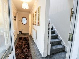 A hallway with a carpet, a staircase, and a radiator.