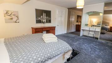 A bedroom with a bed, a dresser, a desk, and a mirror.