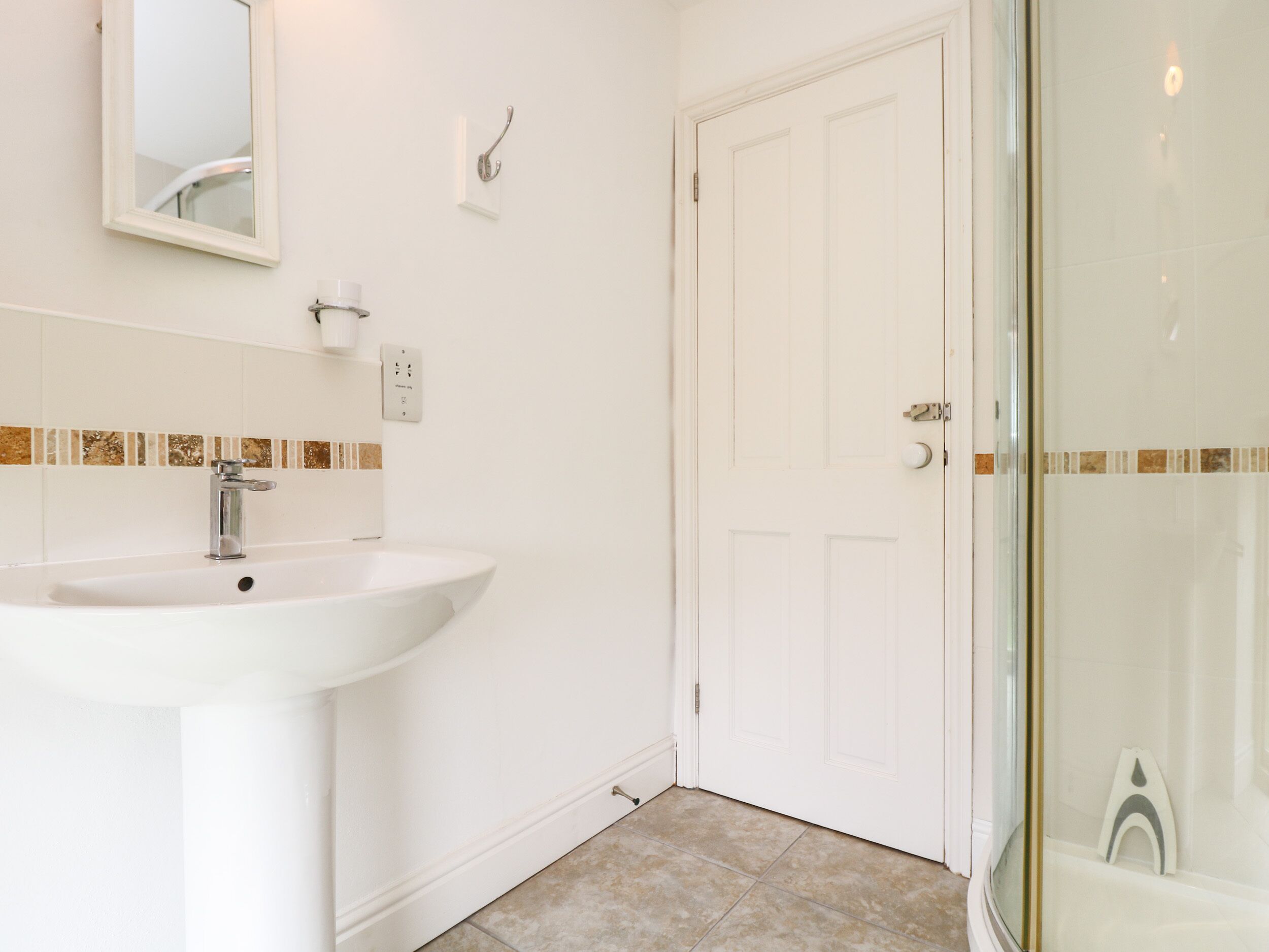 A bathroom with a white sink, a mirror, and a shower area.