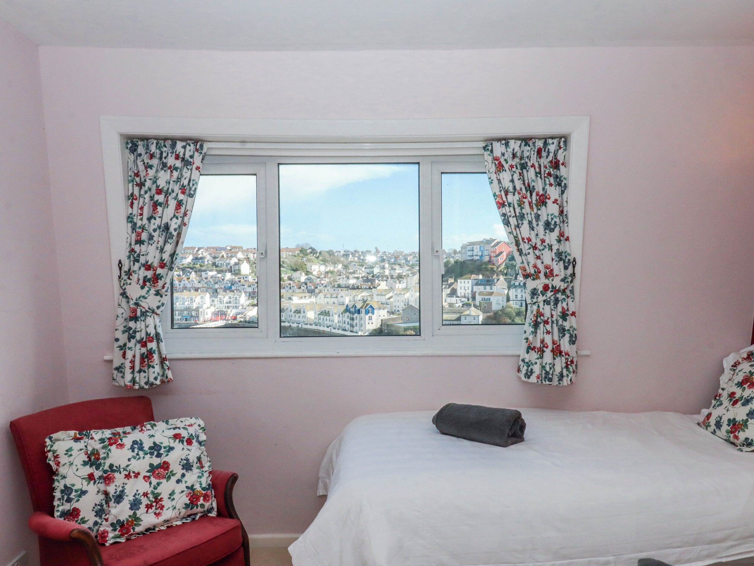 A bedroom with a bed, a chair, and a window with curtains.