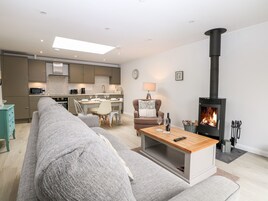 A modern living room with a sofa, a coffee table, a fireplace, and a kitchen in the background.