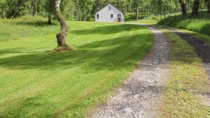 A rural house with a gravel driveway leading to a grassy area. - Birchbank (Grantown-on-Spey)