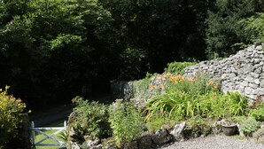A gravel path leading to a stone wall with a wooden gate. - Coachmans Cottage (Grange-over-Sands)