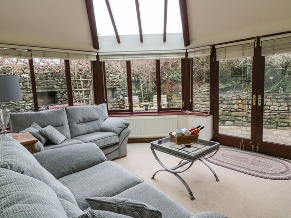 Relax in this stylish room with a sofa, coffee table, and views of lush greenery.