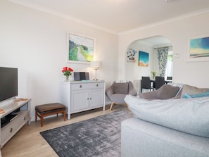 A modern living room with a grey sofa, a white cabinet, a TV, and a lamp. - Gull Cottage (Padstow)