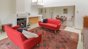 Una sala de estar moderna con chimenea, sofás rojos y un tapete estampado.