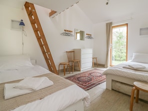 Un dormitorio con dos camas, un escritorio, una silla y una escalera apoyada en la pared.