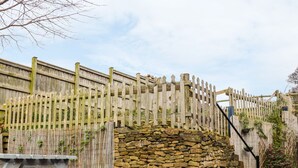 A stone wall with a wooden fence, a metal table, and a grill. - The Old Temperance Hall (Stoke-on-Trent)