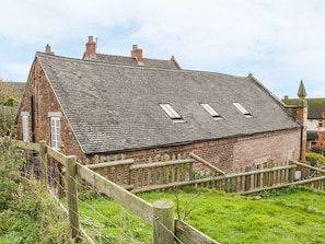 A traditional brick house with a sloped roof, a wooden fence, and a grassy yard. - The Old Temperance Hall (Stoke-on-Trent)