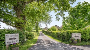 A rural road with directional signs and lush greenery. - Yr Hen Ffald (Swansea)