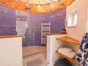 A bathroom with a shower, tiled walls, a wooden bench, and a window. - Lower Tundridge Cottage (Worcester)