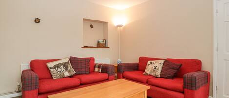A living room with two red sofas, a wooden coffee table, and a floor lamp.