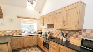 A kitchen with wooden cabinets, a black countertop, a tiled backsplash, and a window.