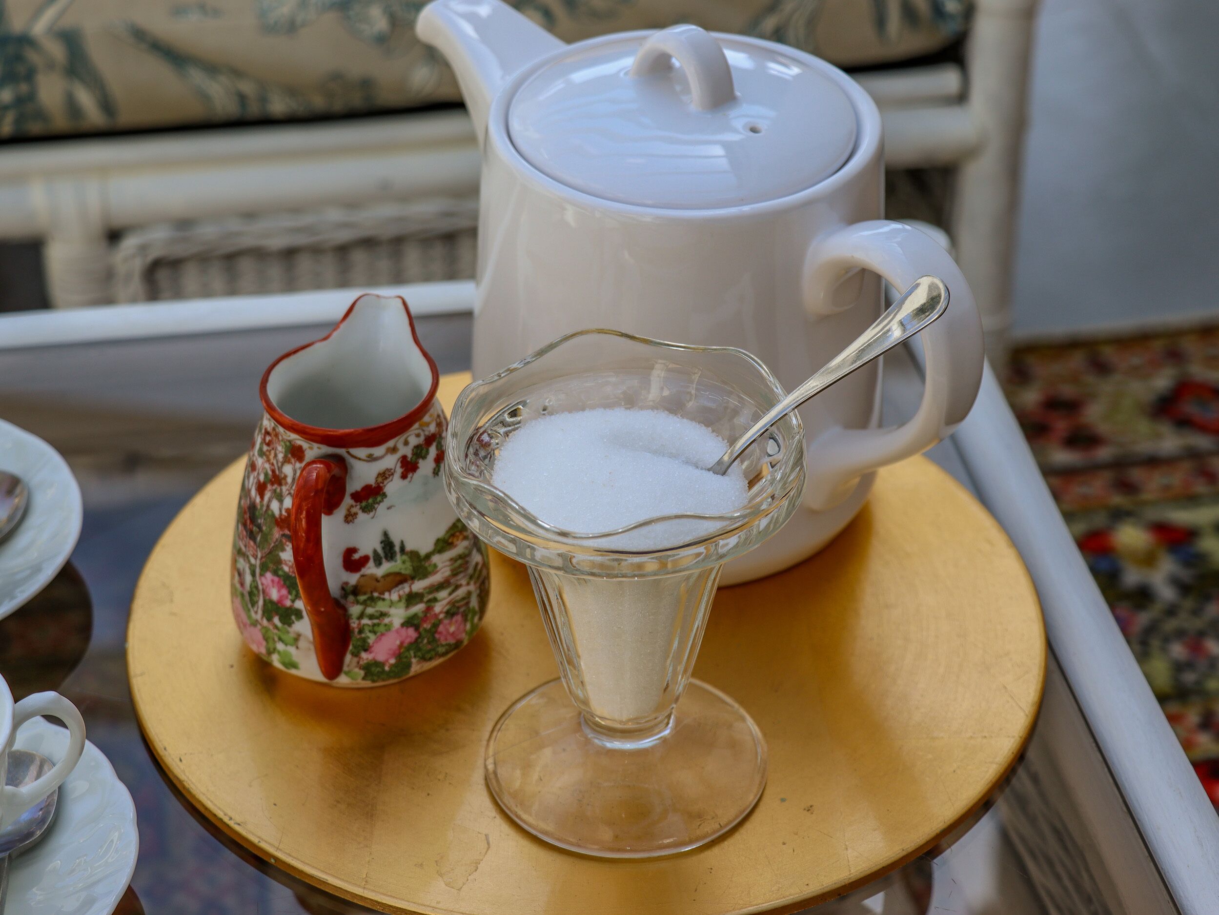 A table with a teapot, a sugar bowl, and a cup.