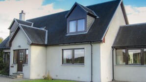 A two-story house with a steeply pitched roof, a chimney, and a well-maintained lawn. - Corriemhor Beag (Grantown-on-Spey)