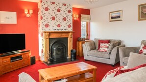 A living room with a fireplace, a television, and a sofa. - Corriemhor Beag (Grantown-on-Spey)