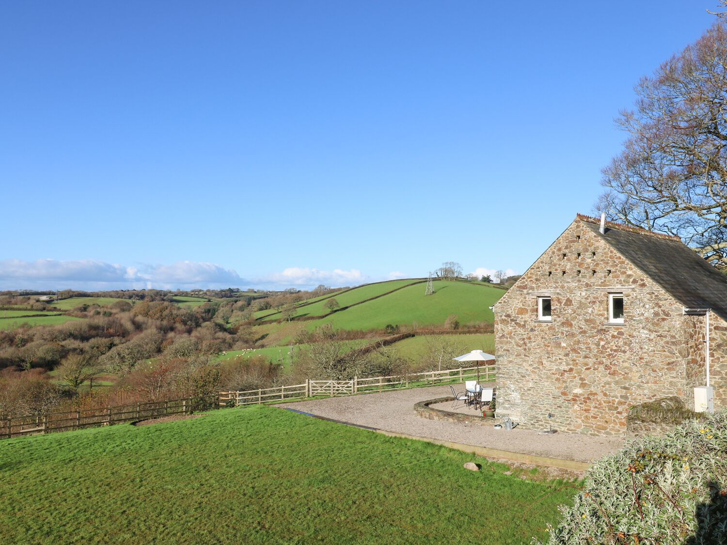 A stone building with a small porch and a fenced yard.