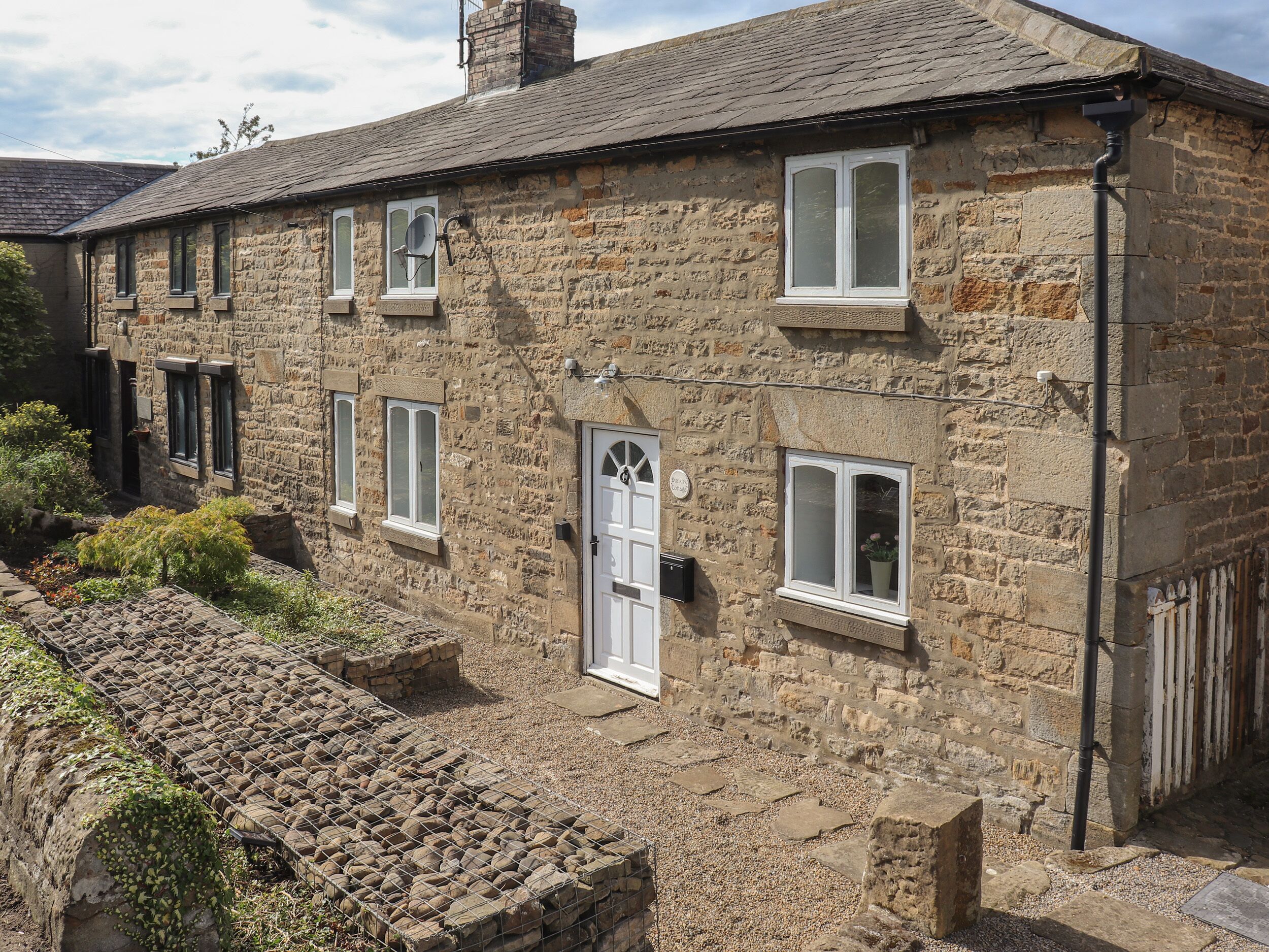 A stone building with multiple windows, a door, and a chimney.