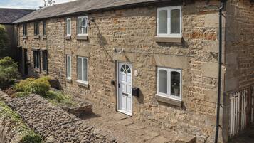 A stone building with multiple windows, a door, and a chimney.