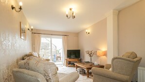 A living room with two armchairs, a sofa, a television, a small table, and a lamp. - Springarth Cottage (Penrith)