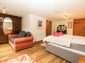 Een slaapkamer met een bed, een stoel, een dressoir, een spiegel en een radiator.