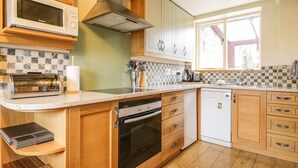 Una cocina con armarios de madera, un microondas, un tostador, una estufa y un lavavajillas.