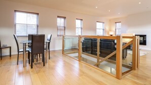 A spacious room with a dining area, large windows, and a staircase. - Wrenville (Keswick)
