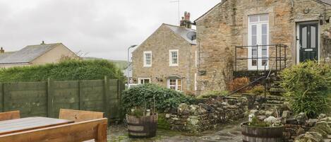 A stone building with a wooden bench and potted plants.