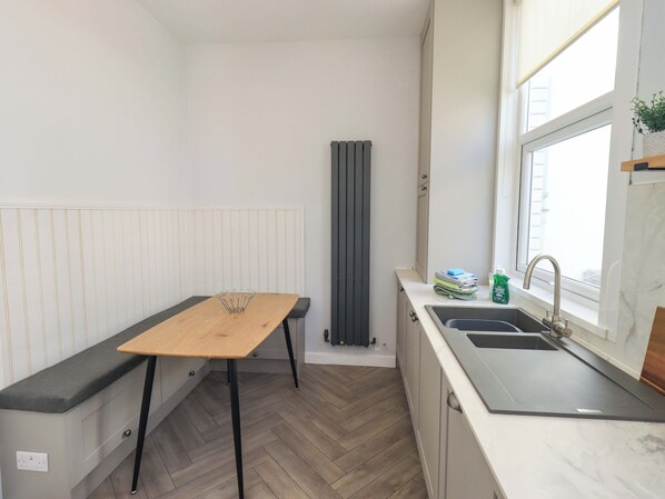 Une cuisine compacte avec une table en bois, un banc intégré, un radiateur et une fenêtre donnant sur un paysage agréable.
