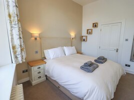 A bedroom with a bed, nightstands, a door, and wall-mounted lights.