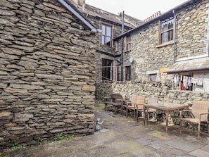 A stone building with a courtyard, wicker furniture, and a hanging clothesline.