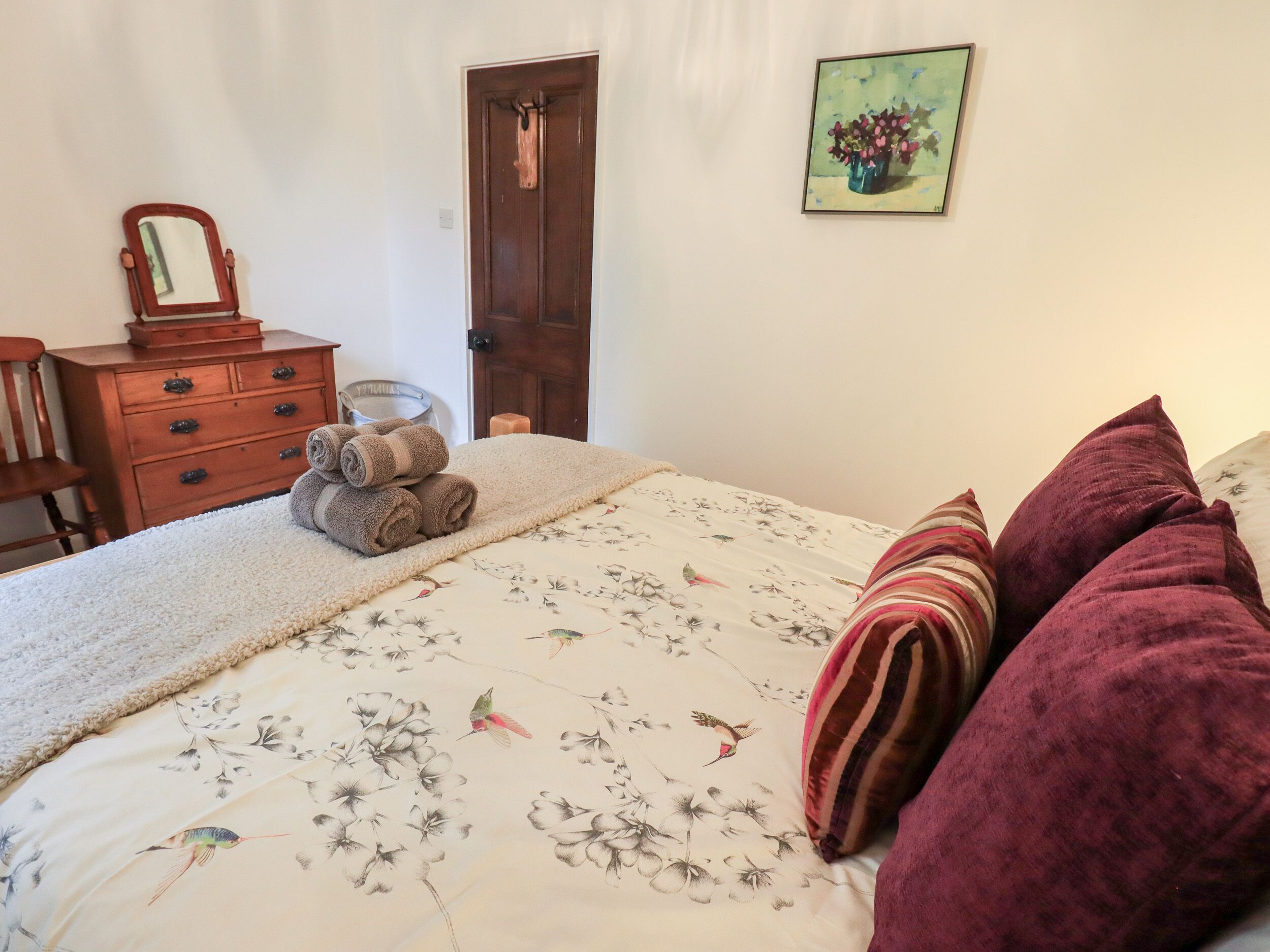 Un dormitorio con cama, cómoda, espejo y puerta.
