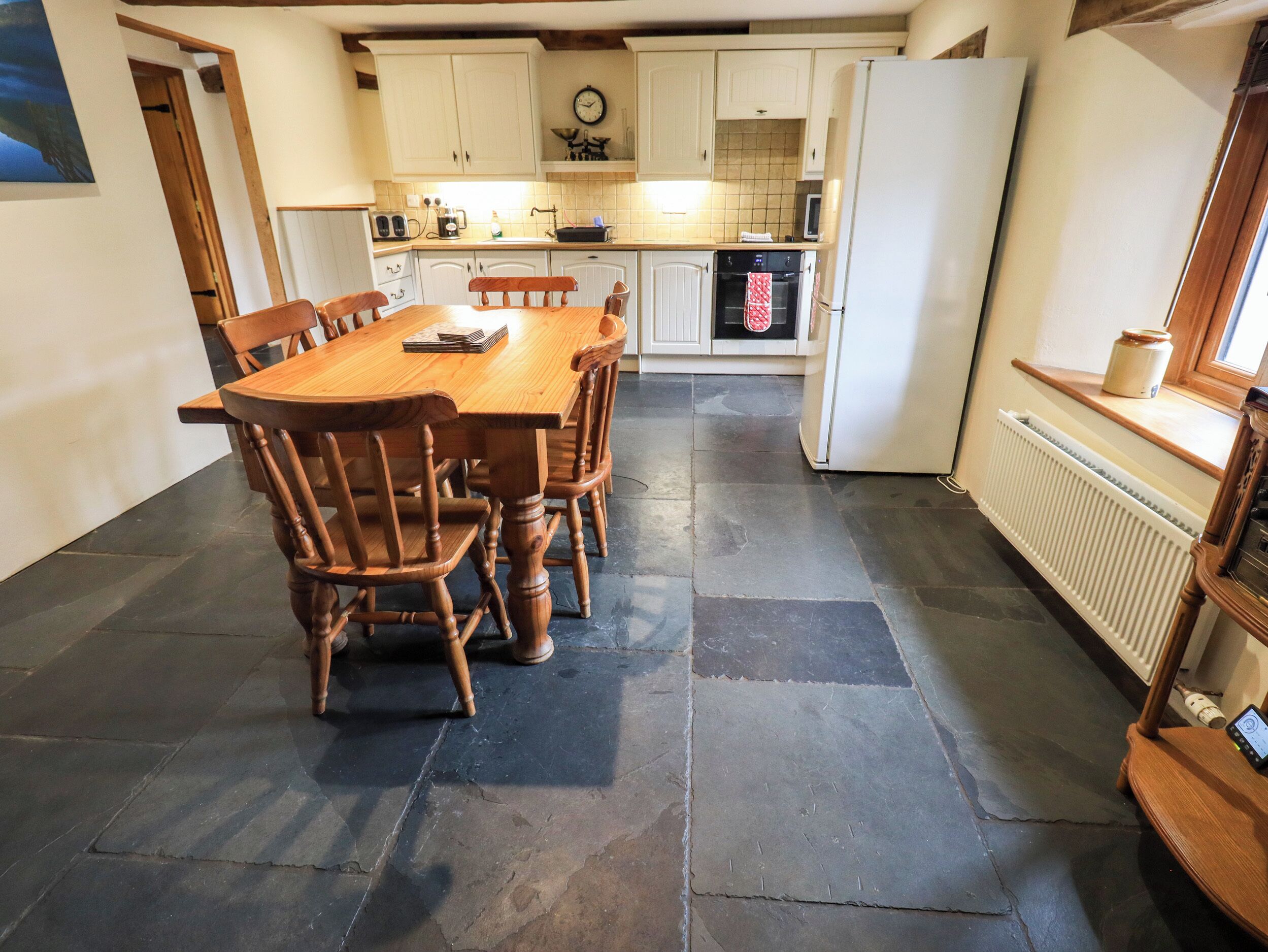 Una cocina con una mesa y sillas de madera, un refrigerador blanco y un salpicadero de azulejos.