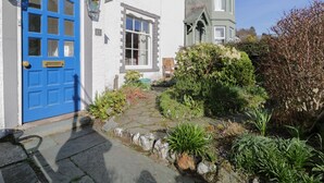 A white building with a blue door labeled "WHITE HOUSE" and a small porch with a chair. - White House (Keswick)