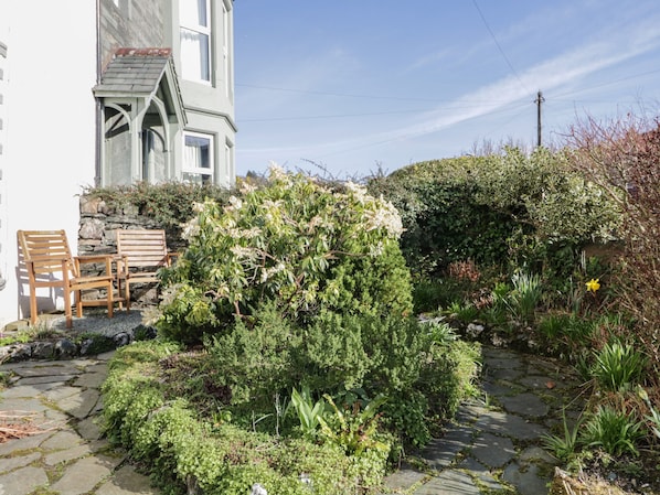 Stroll through the serene garden, featuring a variety of plants and a stone pathway leading to a peaceful seating area.